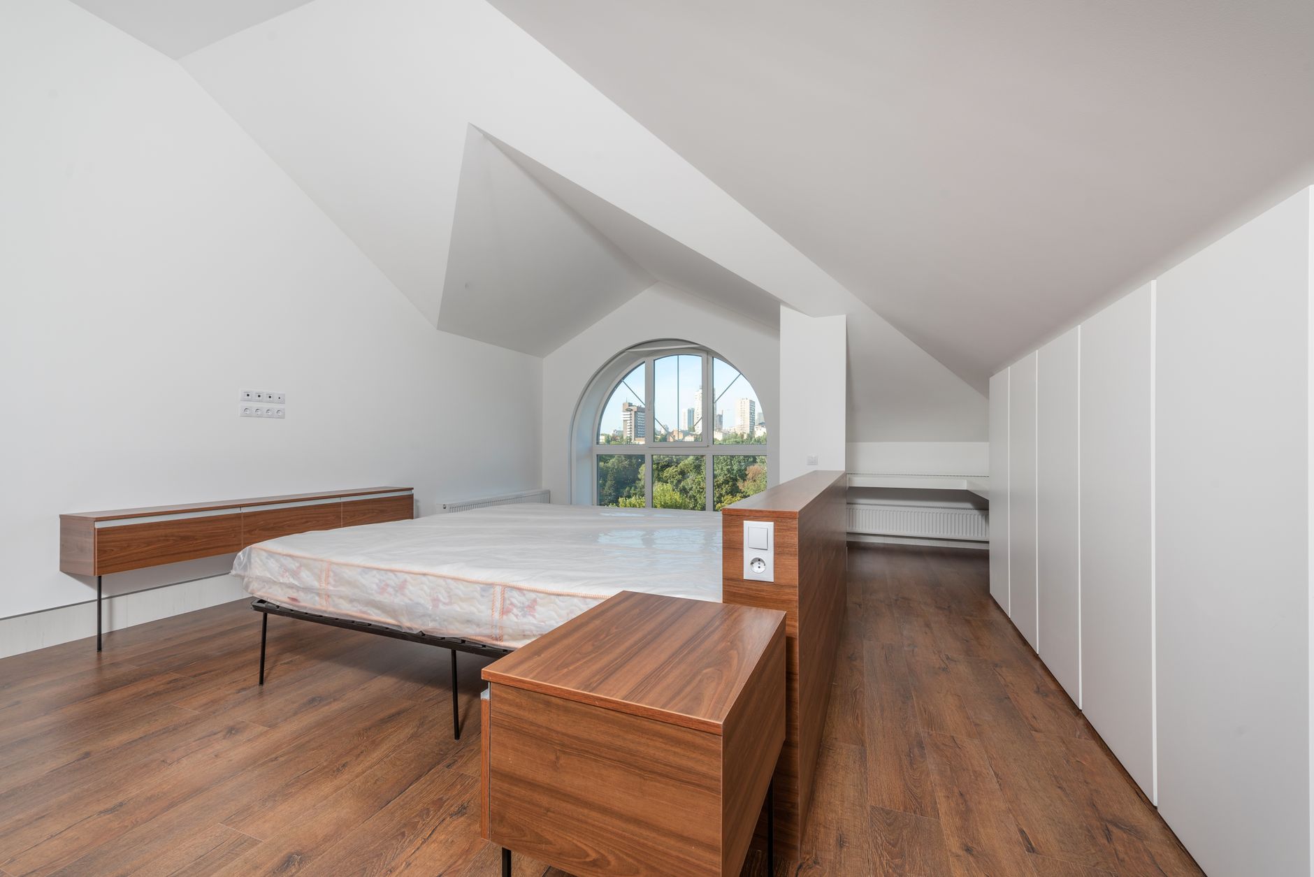 Dormitorio abuhardillado con cama bajo el techo inclinado y una distribución optimizada del espacio.